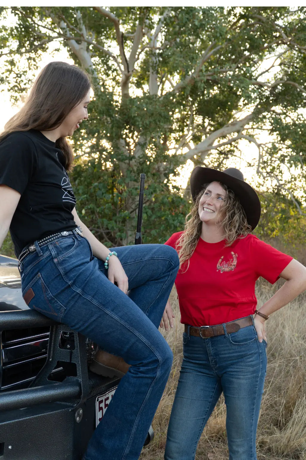two mums standing at front of toyota ute showing tittytees new breastfeeding shirt designs