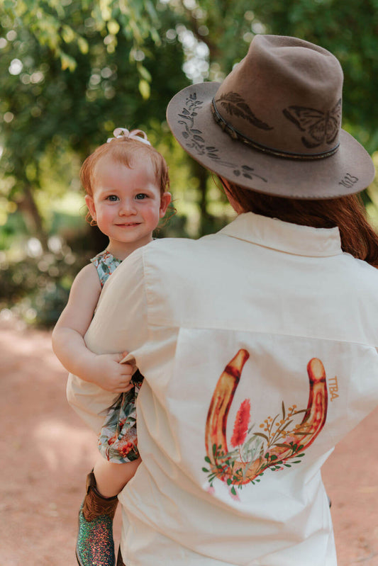 Woman wearing a half-button long sleeve breastfeeding shirt with bottlebrush charm