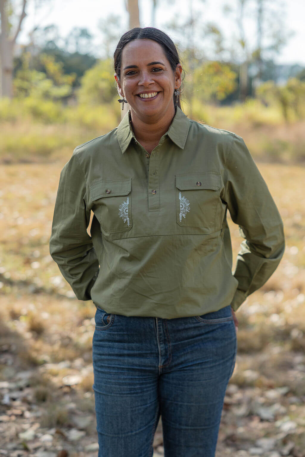 Woman wearing a green shirt and blue jeans standing in a natural setting