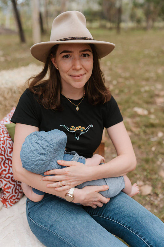 Mum holding and nursing baby wearing tee with cow horns and sunflower print