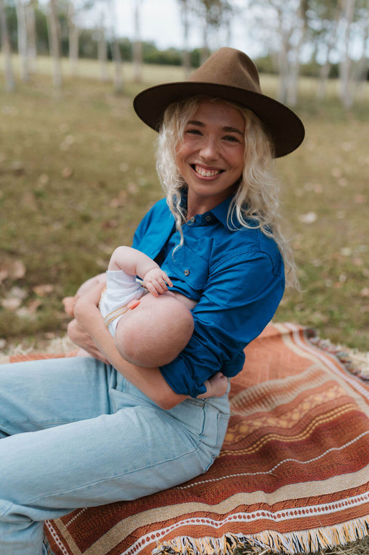 Mum nursing baby sitting on hay bale