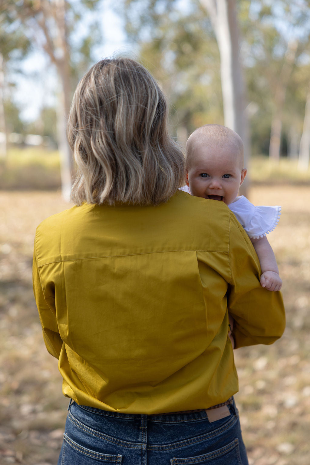 Baby looking over mums shoulder smiling