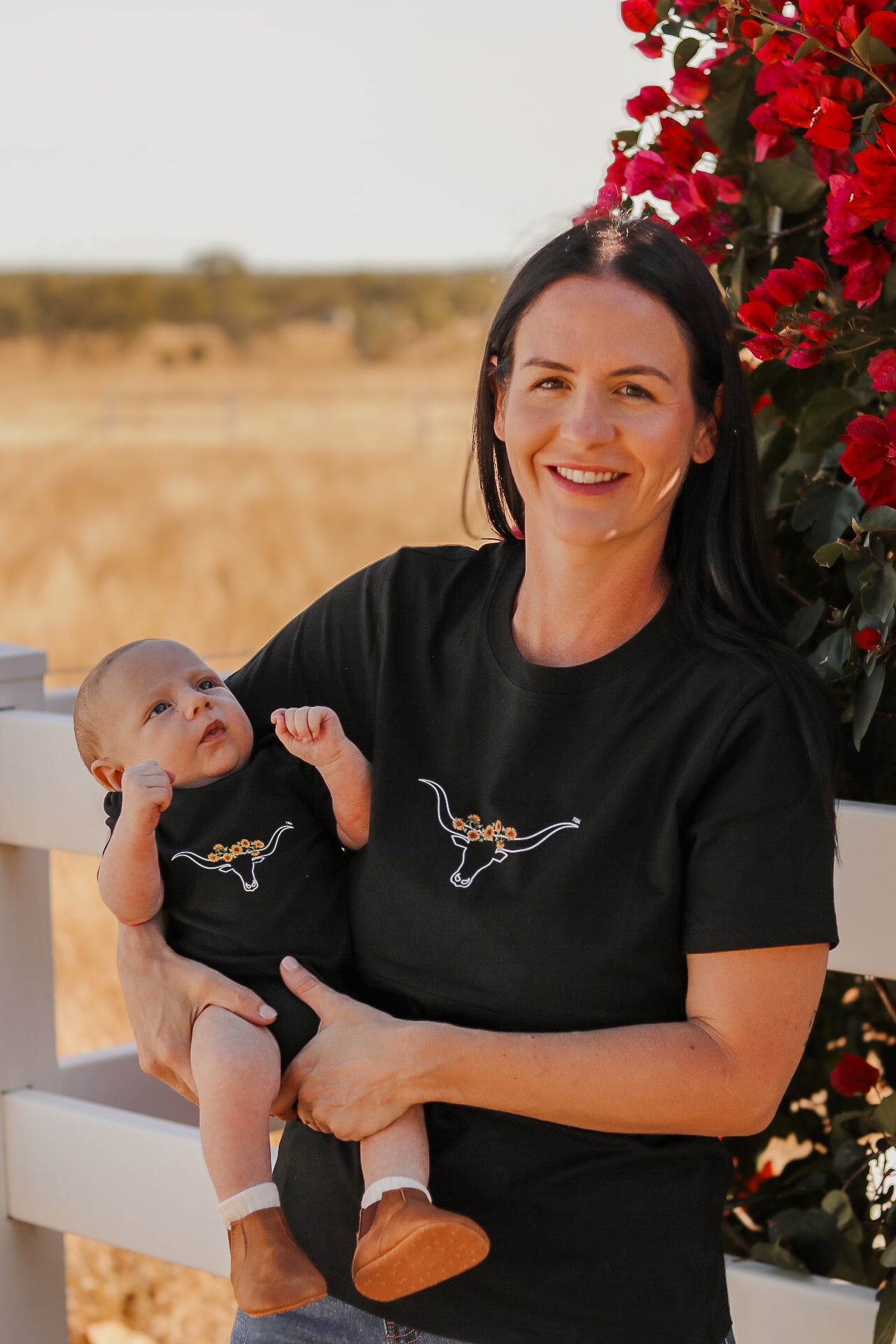 mother holing baby wearing matching onesie with cowhorns and sunflowers print. Mum wearing a breastfeeding tshirt