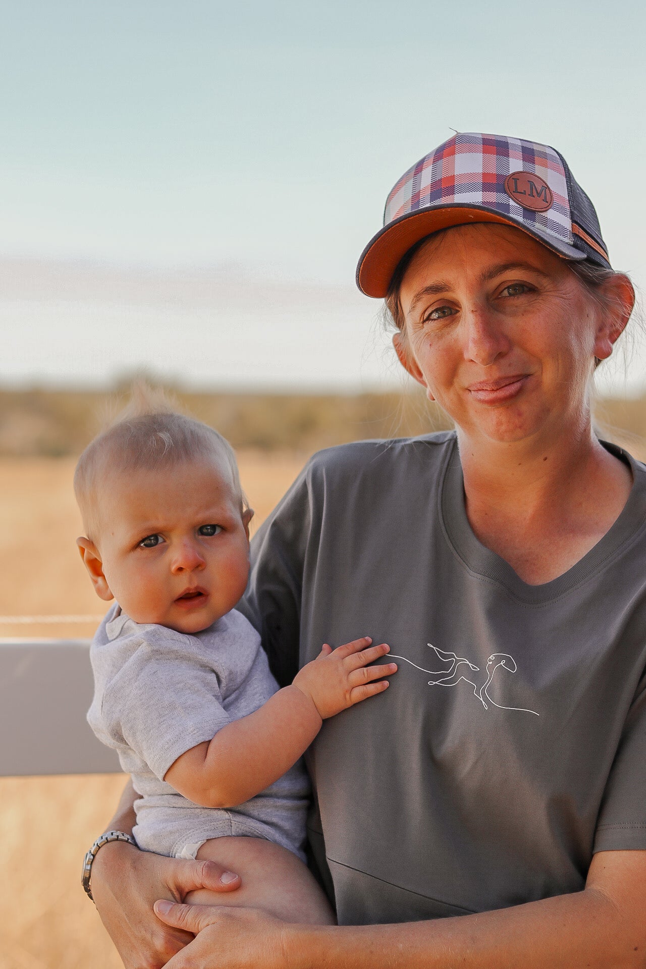 mum holding baby wearing a mum wearing a tittytees breastfeeding shirt outdoors.