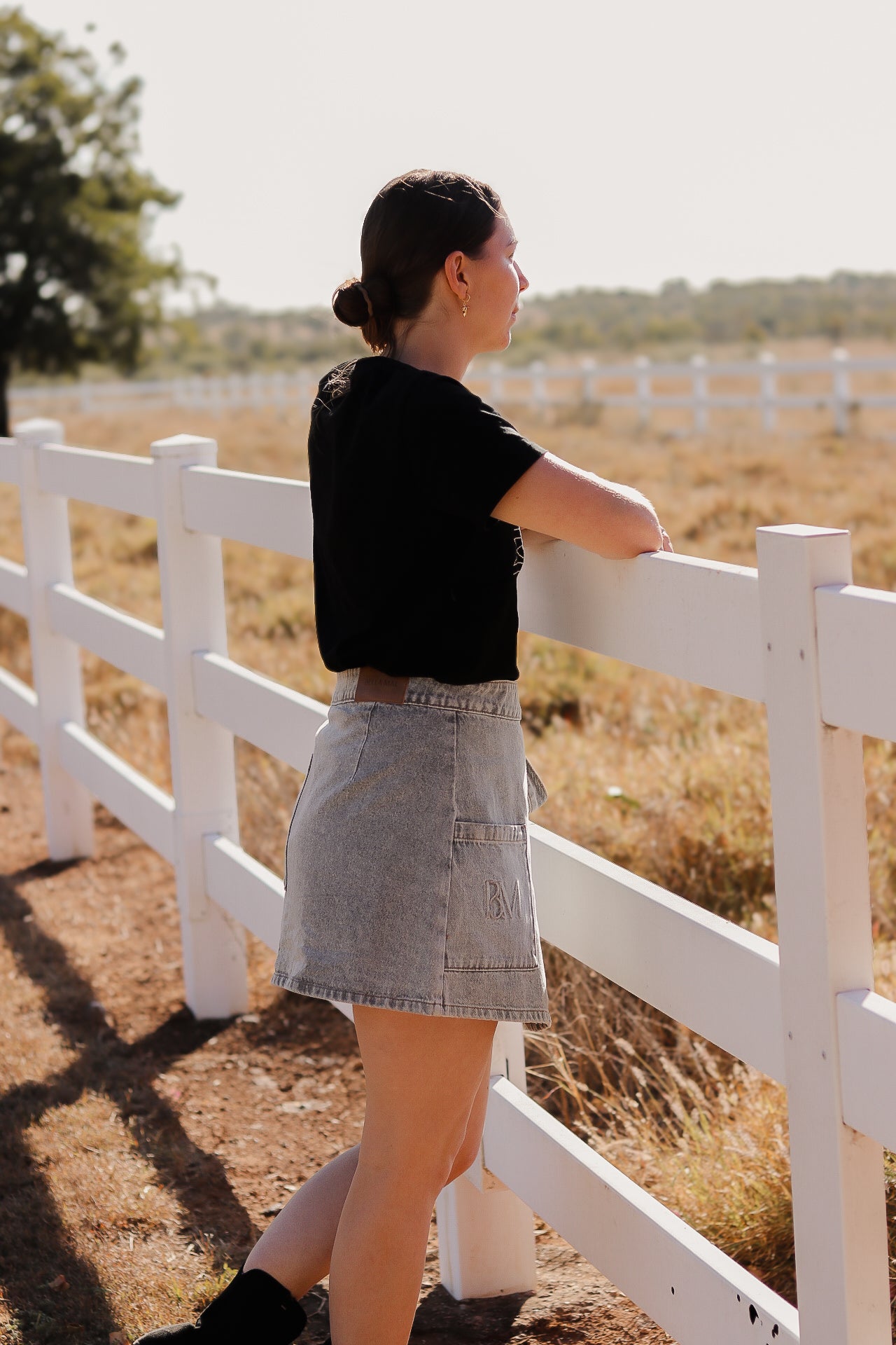 Woman looking onto a rural property wearing a black breastfeeding shirt 