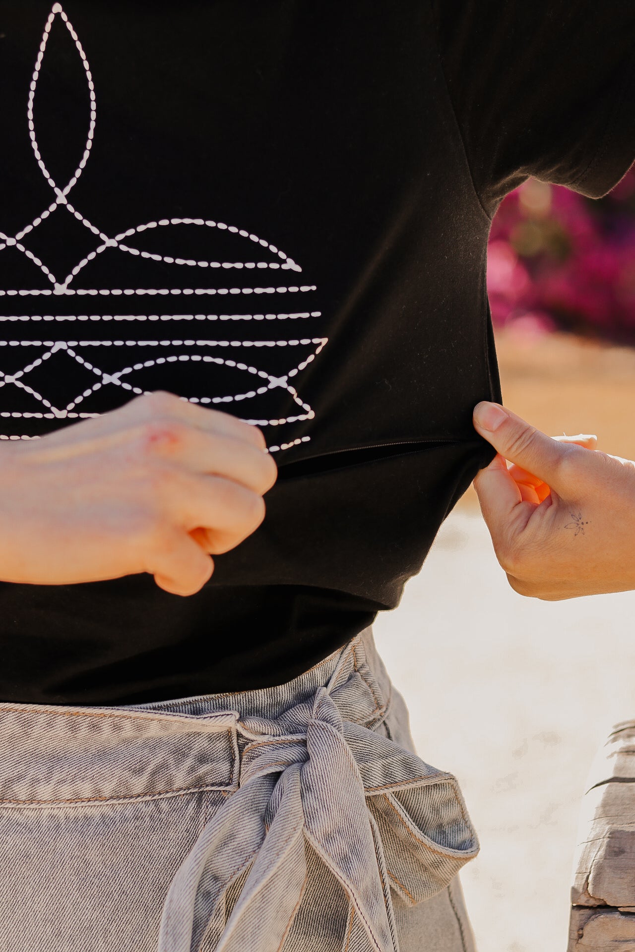 Unzipping a breastfeeding zip on a black t shirt with a boot stitch print