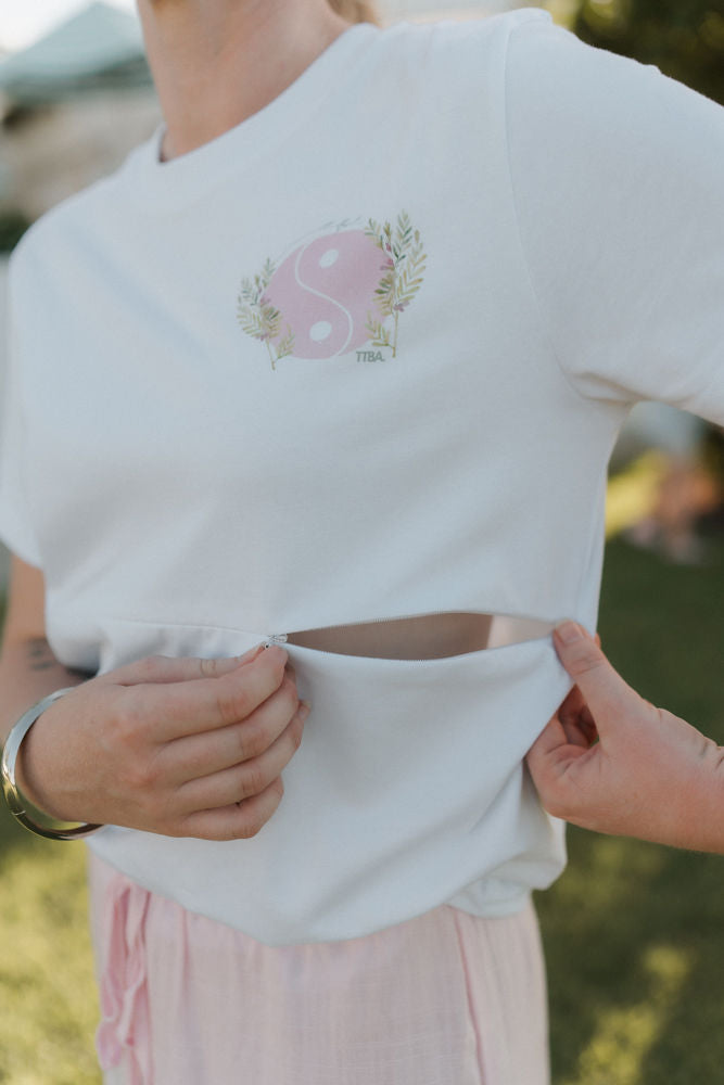 White breastfeeding t-shirt opening the two way zip to show nursing access function. 