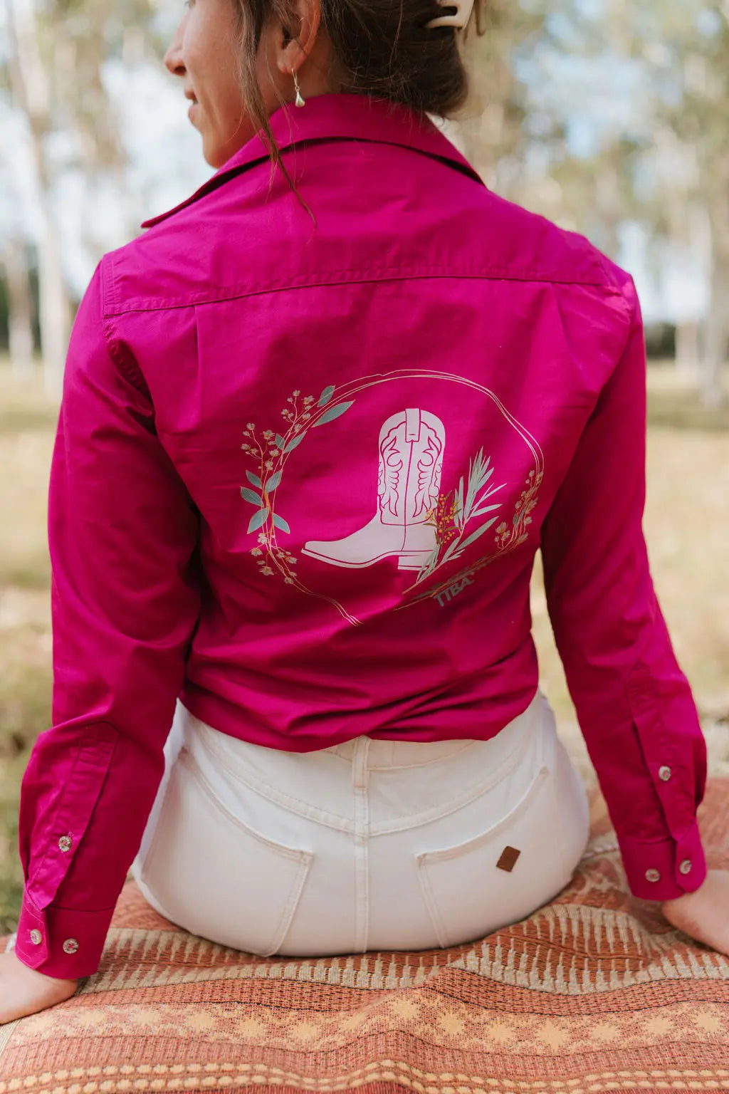 Person wearing a pink jacket with a white boot design outdoors