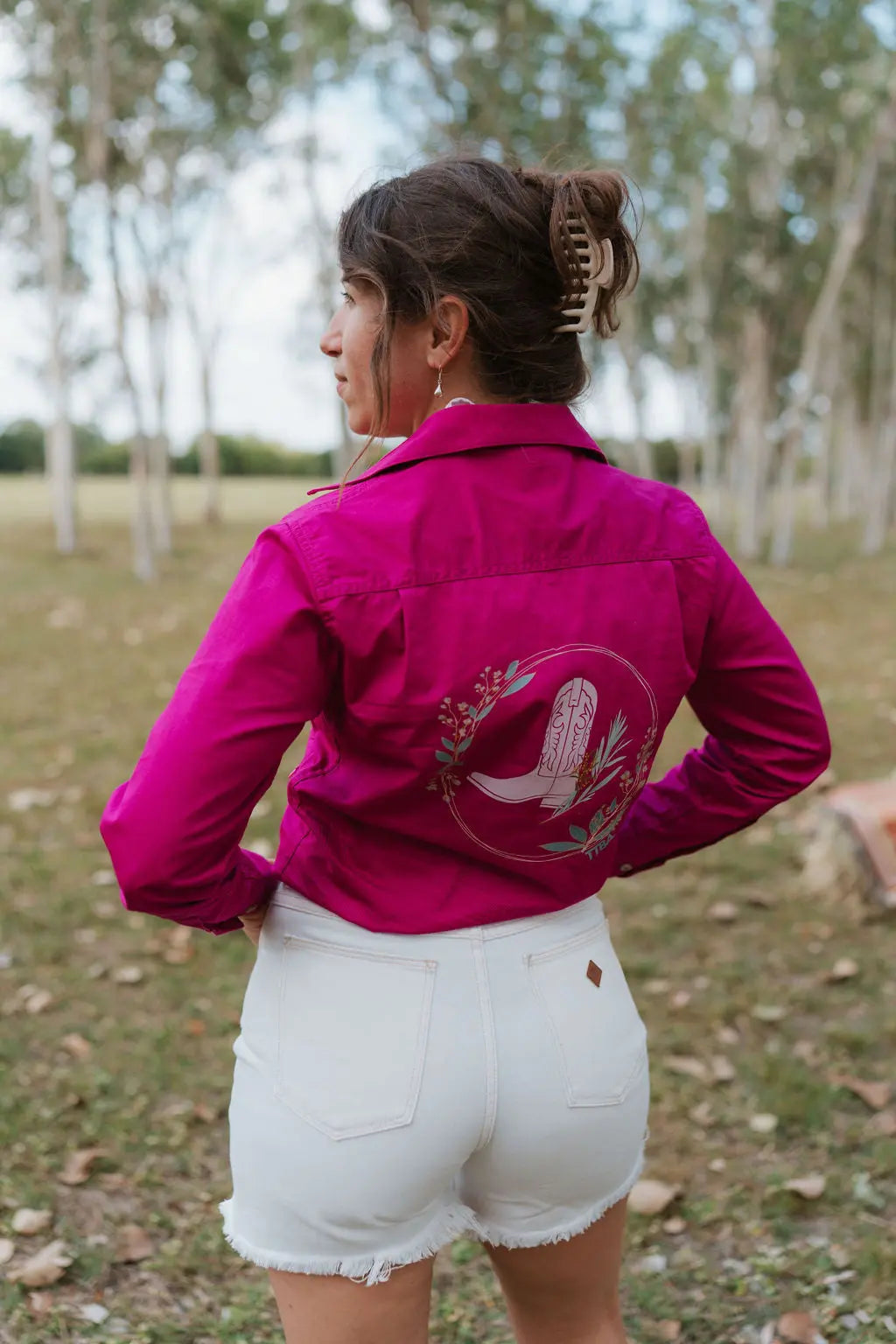 Person wearing a bright pink work shirt with a design outdoors
