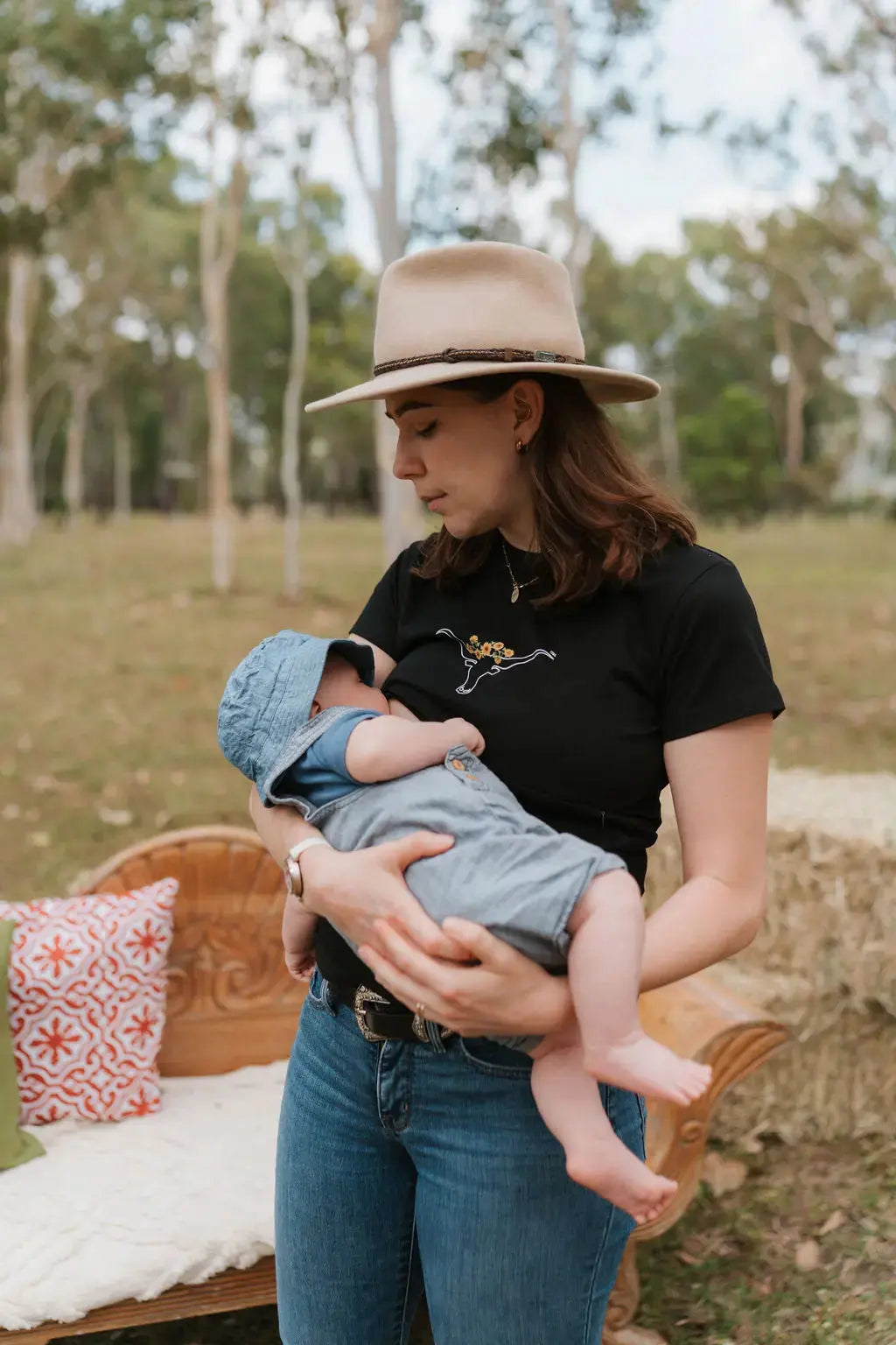 Mum standing wearing black breastfeeding tee with cow horns and sunflowers outdoors 