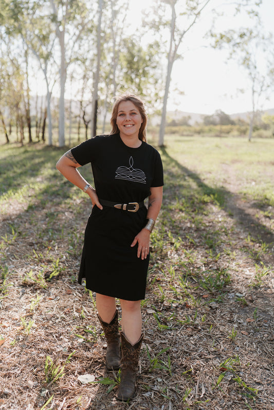 Woman in a black t-shirt breastfeeding dress standing outdoors with trees in the background