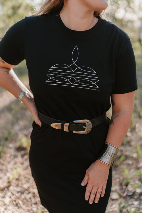 Person wearing a black t-shirt  nursing dress with a white boot stitch design outdoors