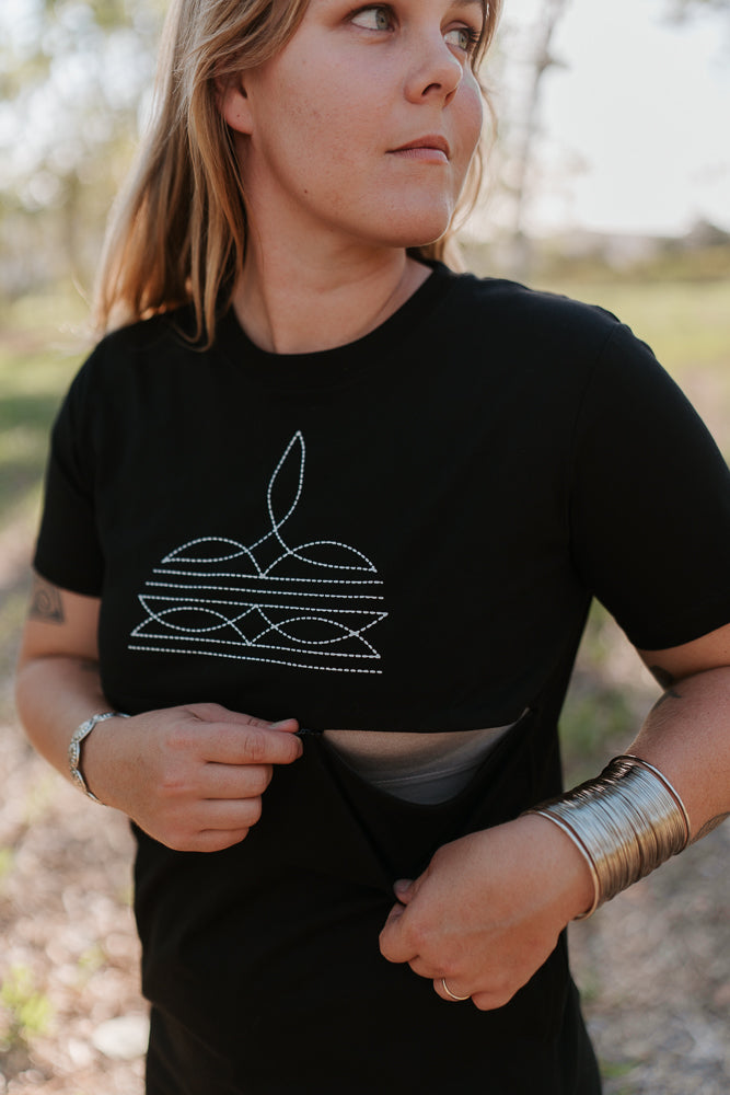Person wearing a black breastfeeding t-shirt dress with a white design outdoors