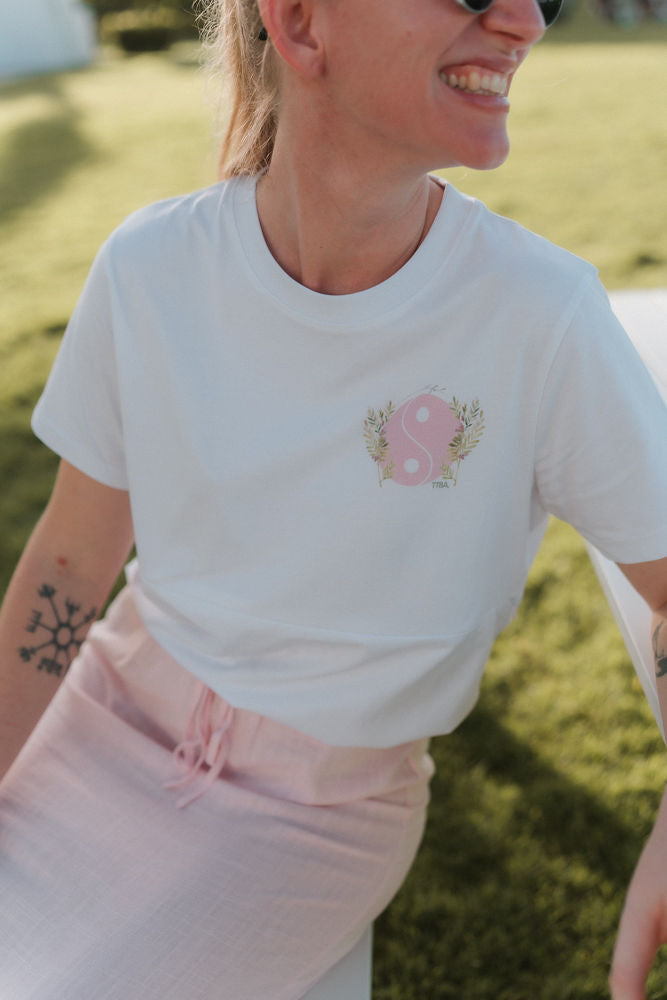 Person wearing a breastfeeding white t-shirt with a pink yin and yang design outdoors