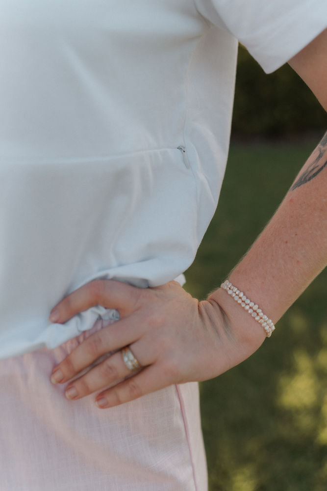 Person wearing a white nursing friendly shirt showing the nursing zip up close.