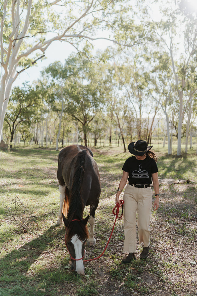 Person walking a horse in a wooded area