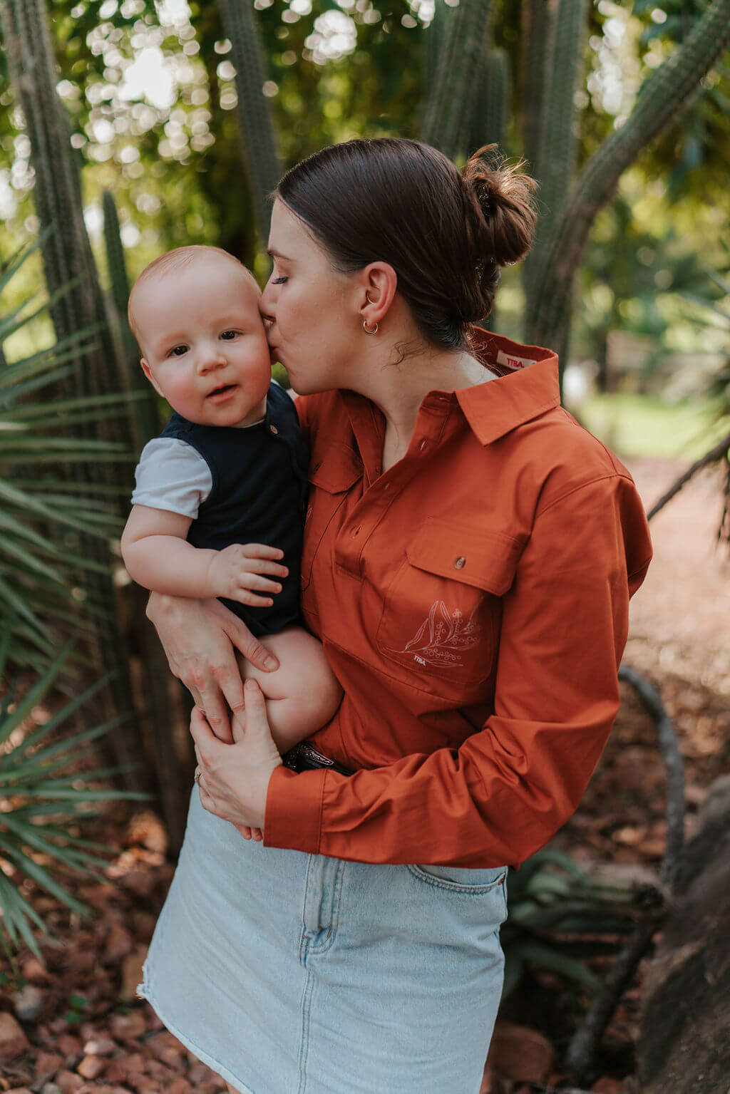 Mum holding and kissing baby outdoors