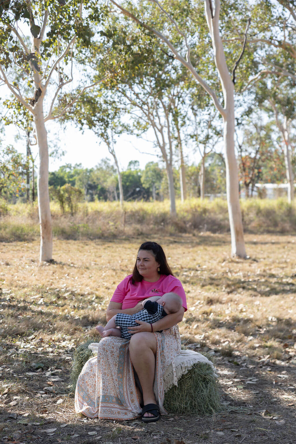 Mum sitting on hay bale breastfeeding baby