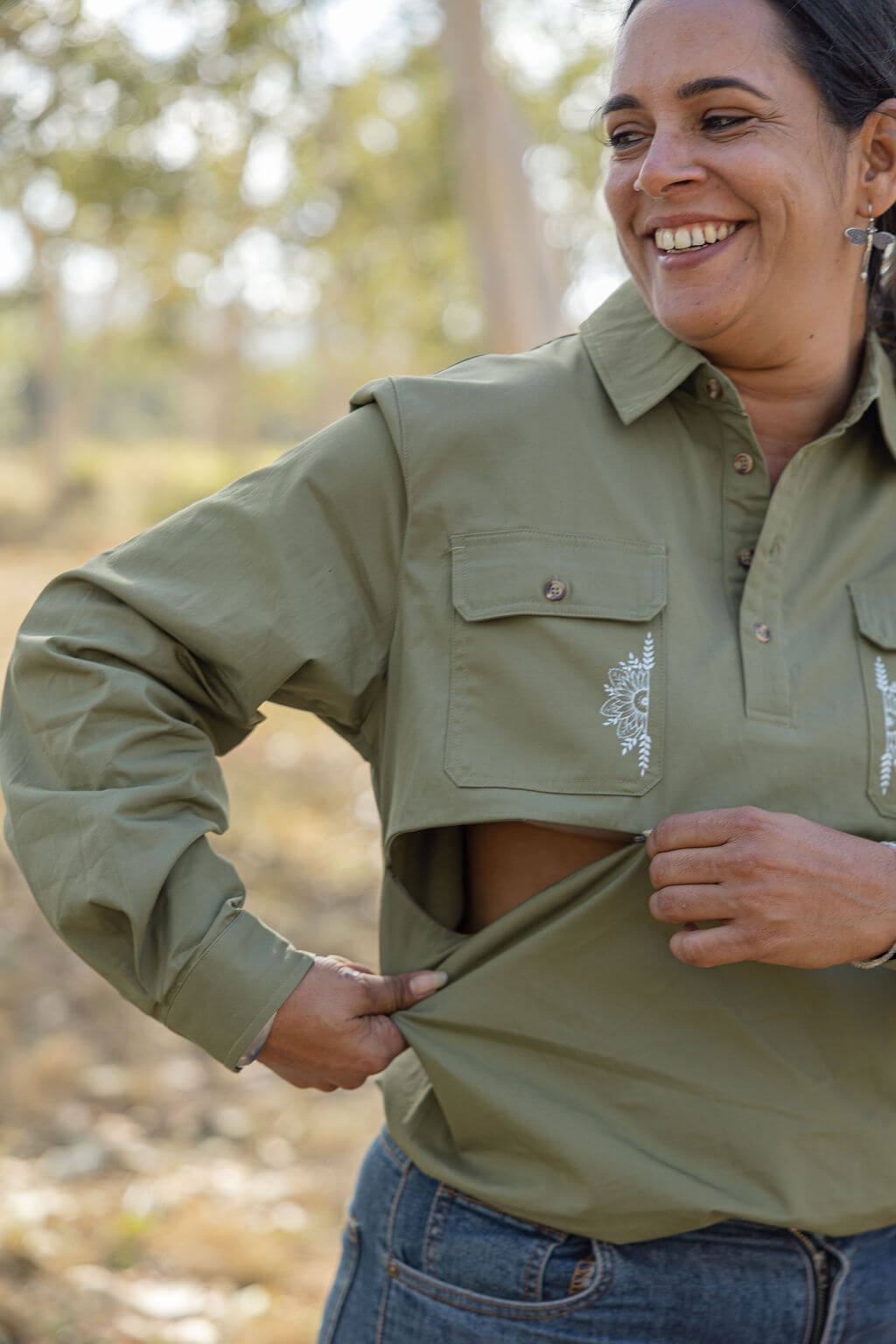 Woman wearing a green shirt with a logo, standing outdoors.