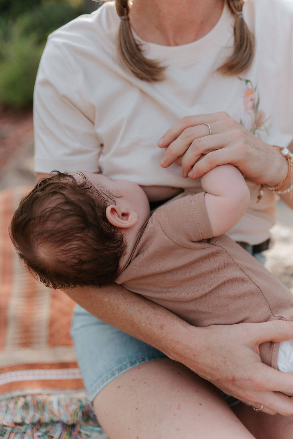 Mum holding baby hand while breastfeeding 