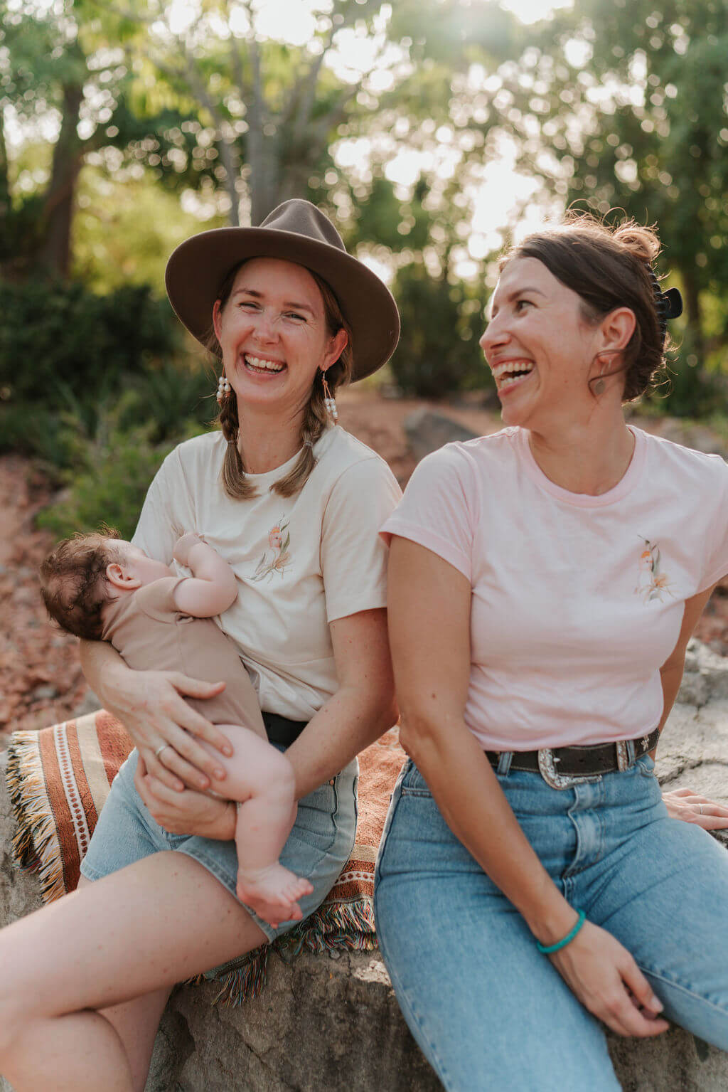 Mum nursing baby sitting next to sister in matching shirts 