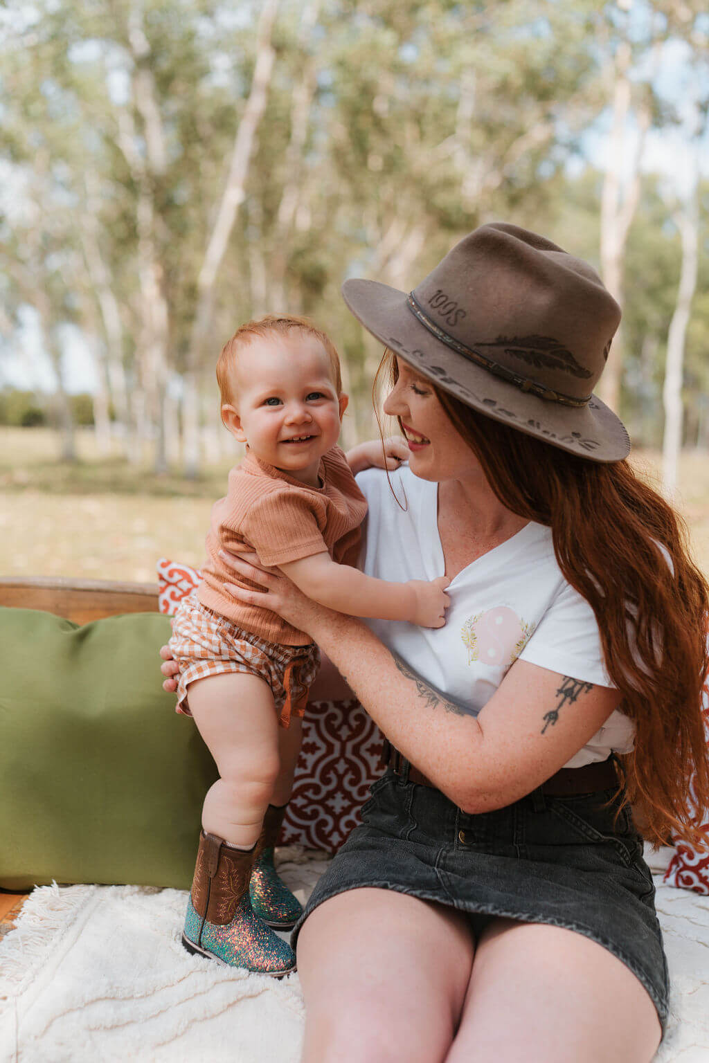 Woman holding a baby outdoors with trees in the background