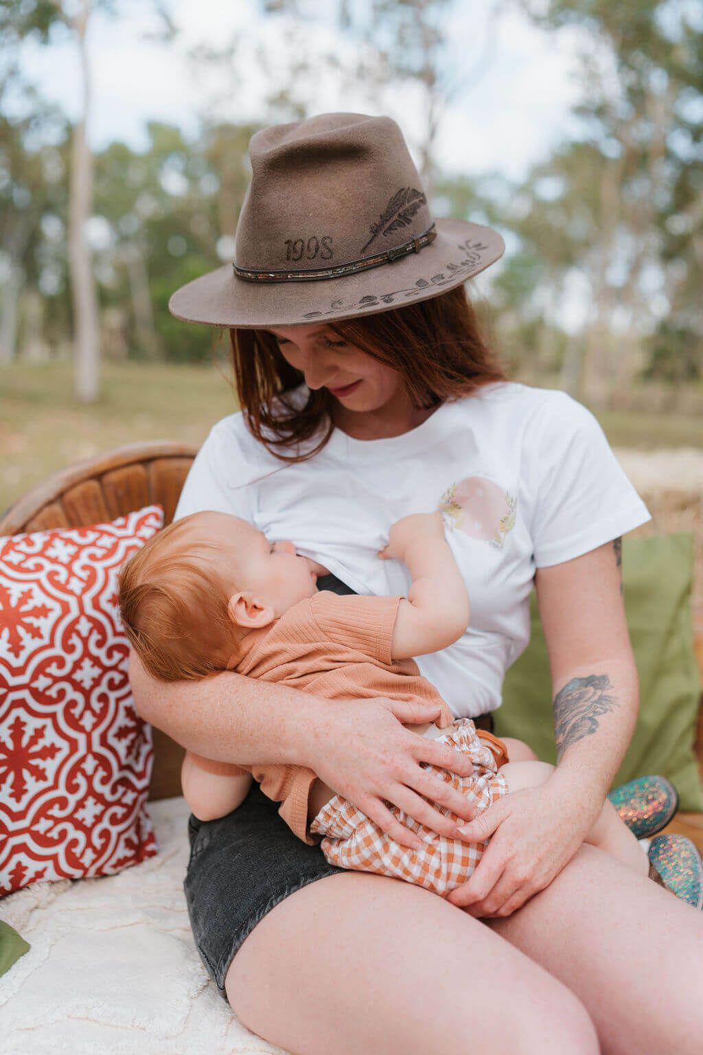 Woman wearing a hat holding a baby outdoors